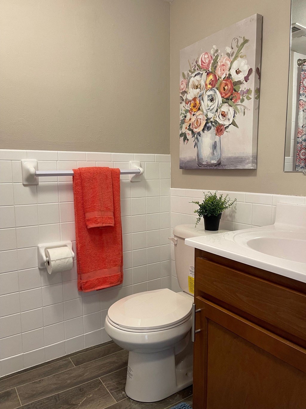 a bathroom with a toilet and a sink and a painting of flowers