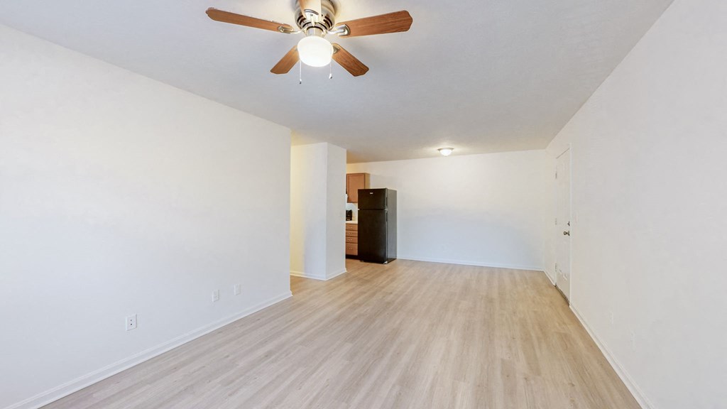 a living room with white walls and a ceiling fan