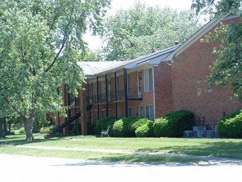 a red brick building with a lawn and trees