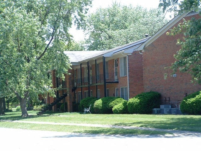 a red brick building with a lawn and trees