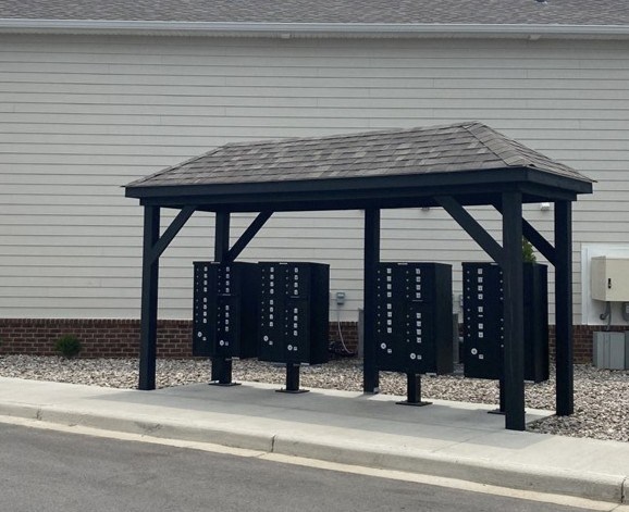 A bus stop shelter with a roof and four benches.