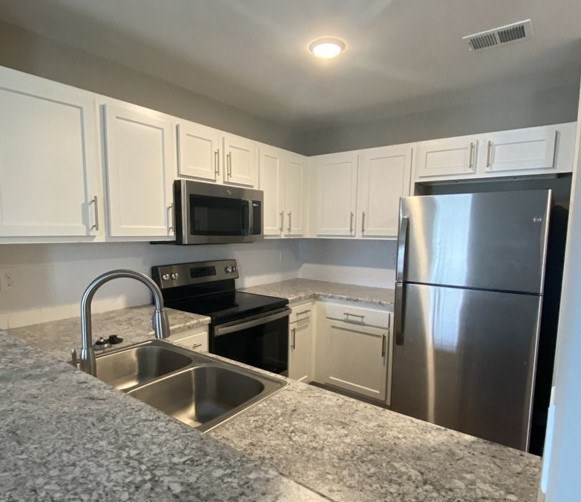 A kitchen with a stainless steel refrigerator and sink.