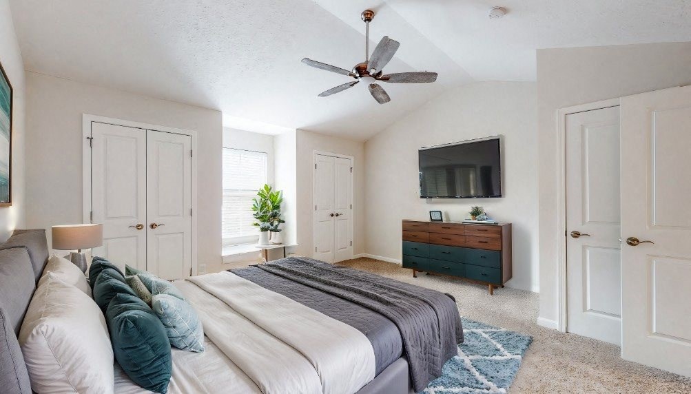 A bedroom with a bed, a dresser, and a ceiling fan.
