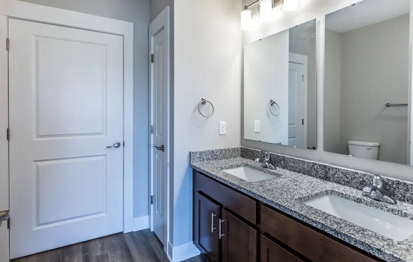 A bathroom with a white door, a mirror, and a sink.