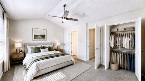 A bedroom with a large bed and a closet full of clothes.