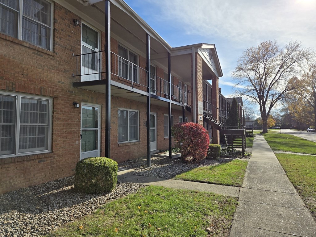 A row of apartment buildings with a sidewalk in front.