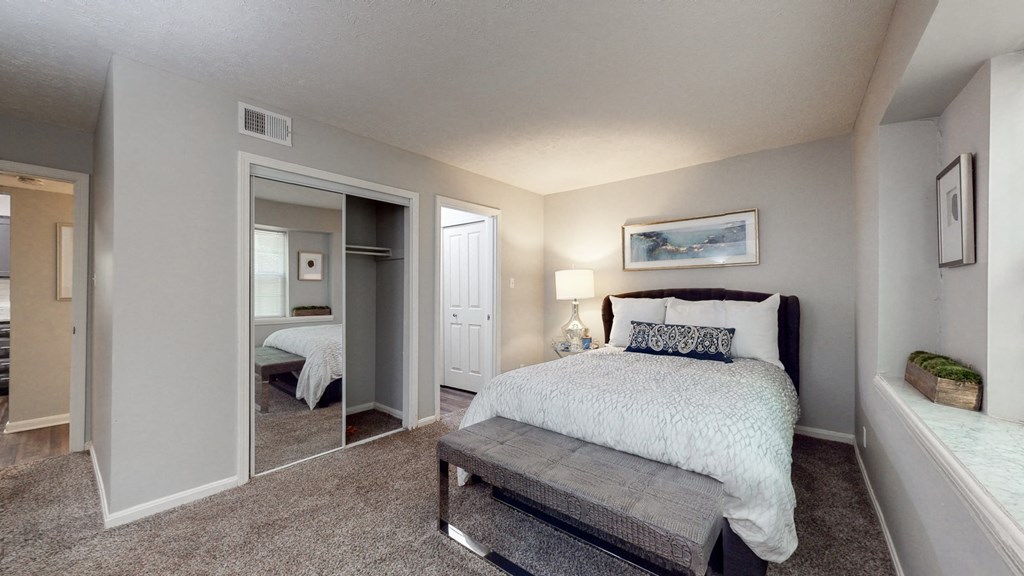 a bedroom with a bed and a mirrored closet