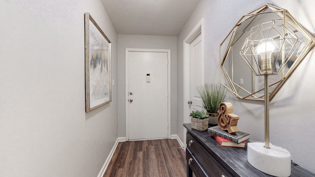 an entryway with a lamp and a door to a bedroom