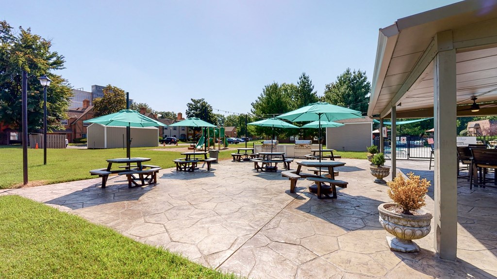 a patio with picnic tables and umbrellas in a park