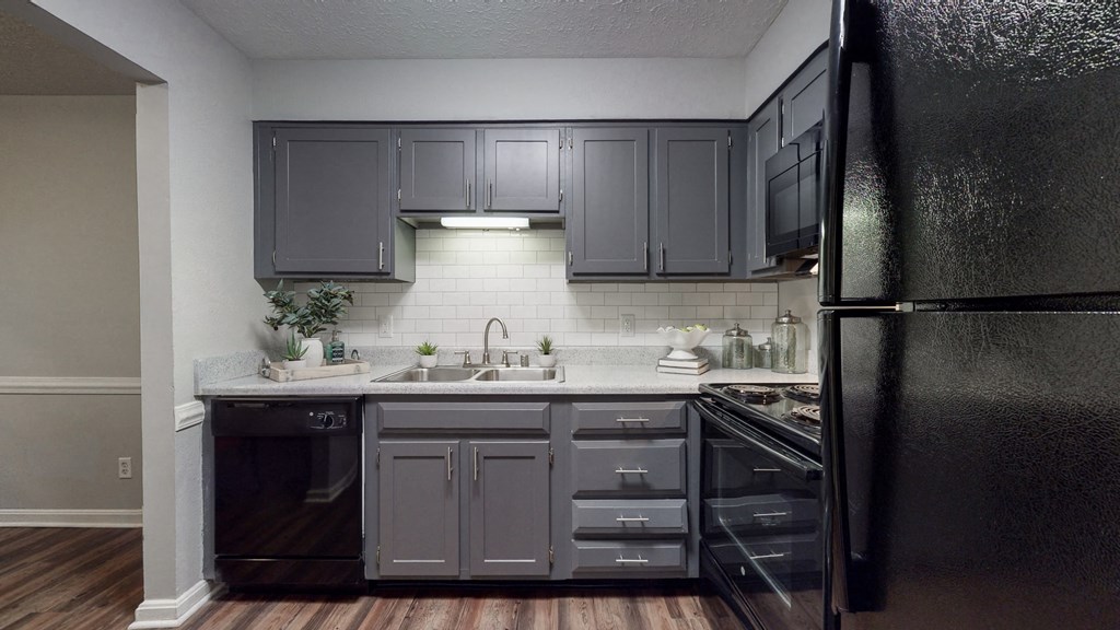an empty kitchen with black appliances and gray cabinets
