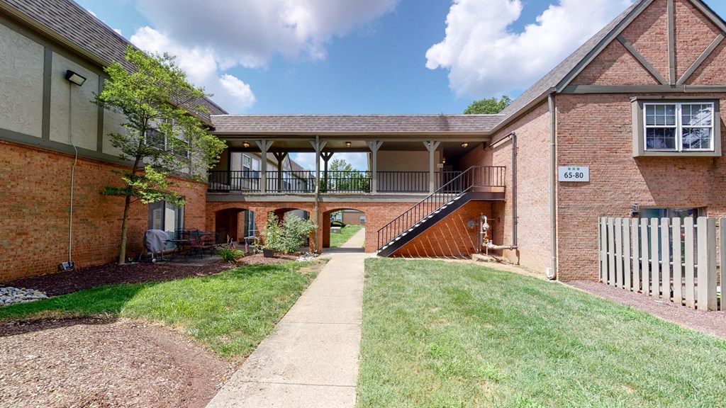 the front of a brick house with a yard and a balcony