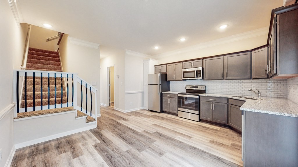 a kitchen with stainless steel appliances and a staircase in a new home