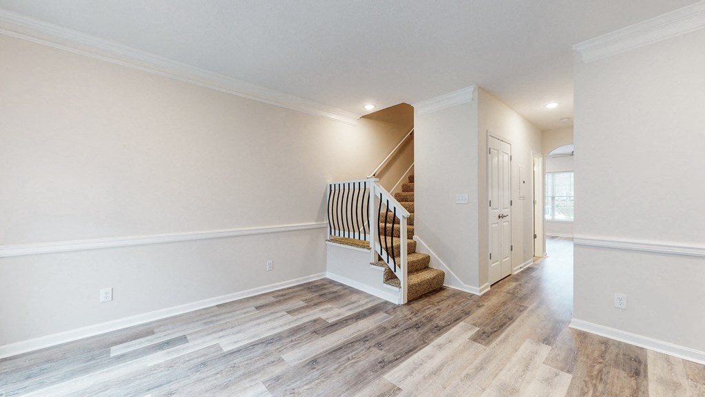 a renovated living room with stairs and a hallway with white walls and wood floors
