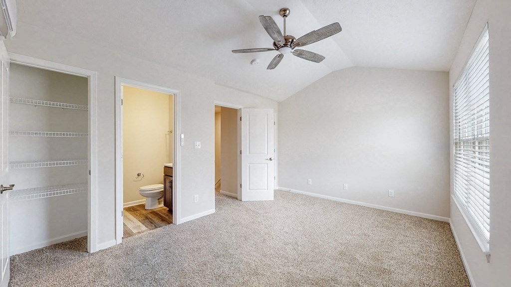 an empty living room with a ceiling fan and a toilet
