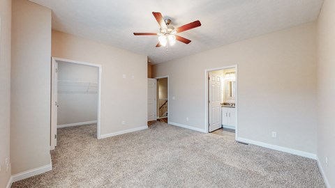 A spacious room with a ceiling fan and carpeted floor.
