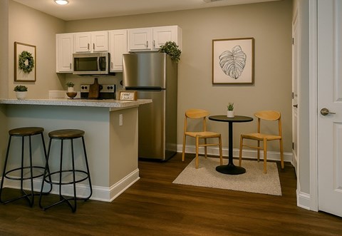 A kitchen with a refrigerator, a microwave, and a table with two chairs.
