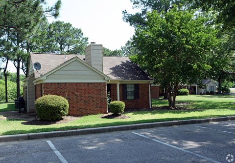 a small brick house on the side of a parking lot