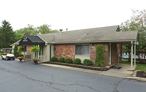 A small brick building with a black awning and a white golf cart parked in front.
