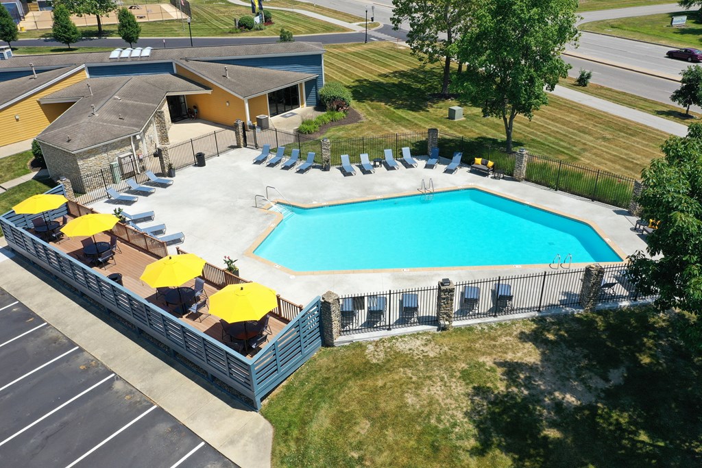 an aerial view of a pool with a fence and patio umbrellas