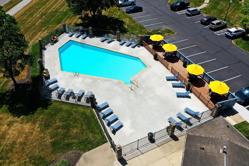 an aerial view of a resort style pool with lounge chairs and umbrellas