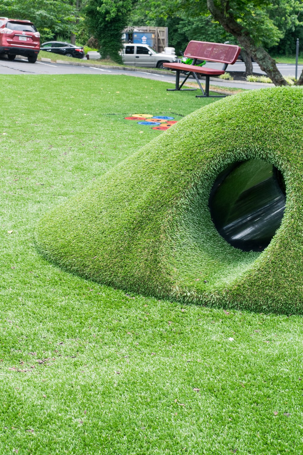 a green tunnel sculpture in the grass in a park