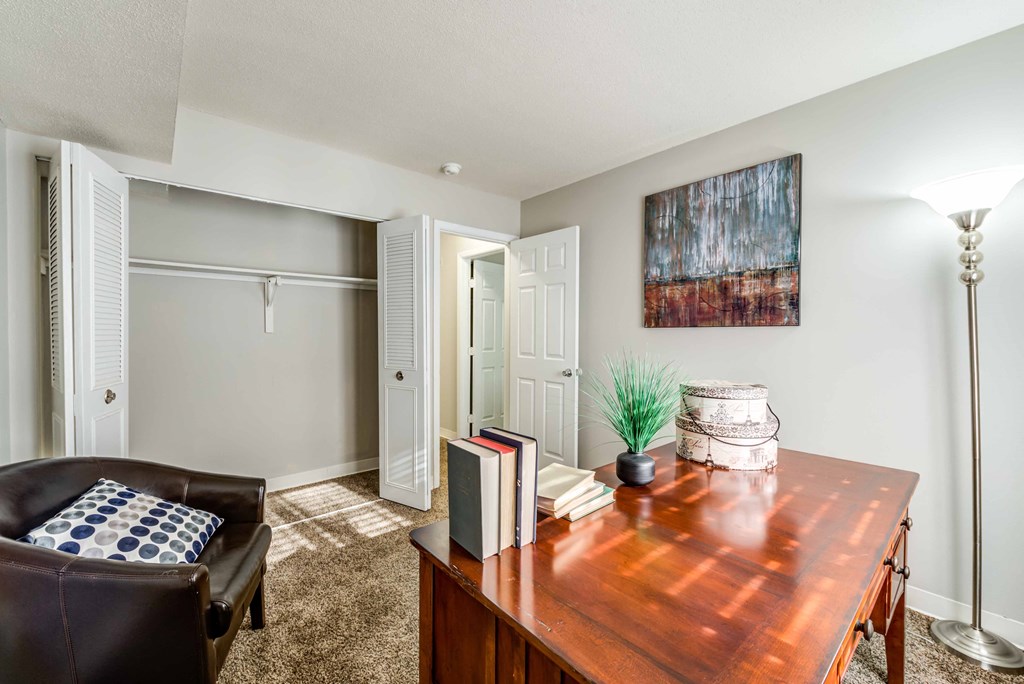 a living room with a wooden desk and a leather chair