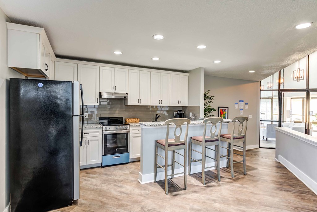 a kitchen with white cabinets and a bar with chairs