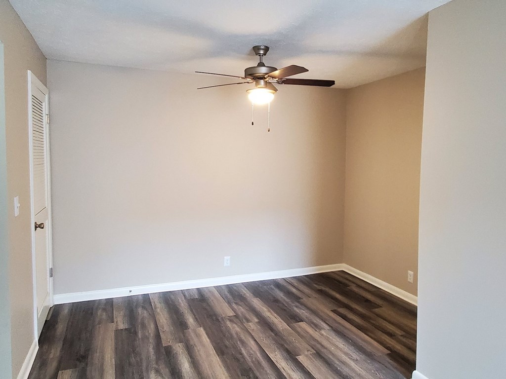 A room with a ceiling fan and wooden flooring.