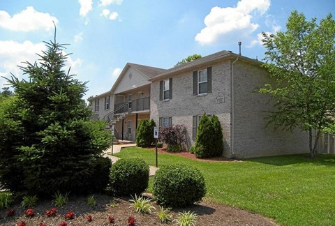An apartment building with a well-maintained lawn and a small garden in front.
