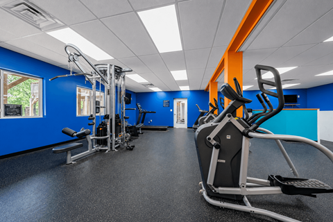 A gym with a row of exercise machines.