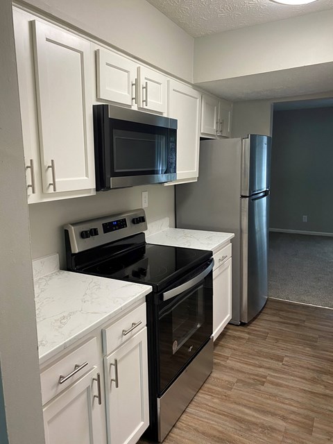 A kitchen with white cabinets and a black microwave.