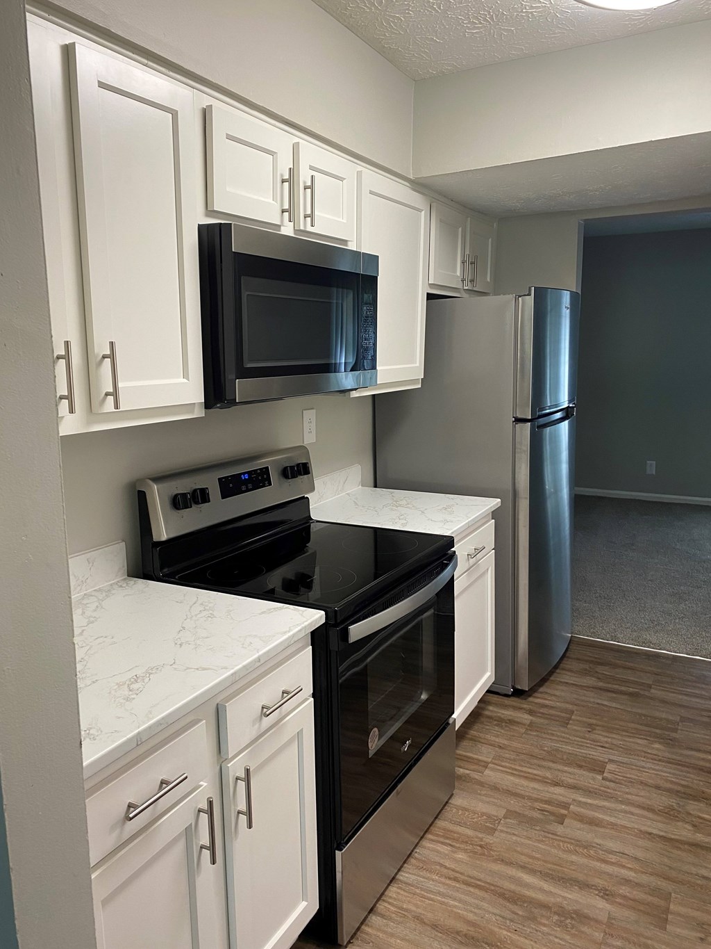A kitchen with white cabinets and a black microwave.
