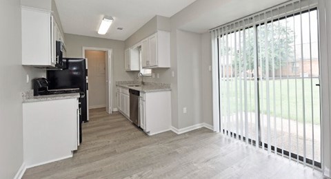 A kitchen with white cabinets and a black refrigerator.