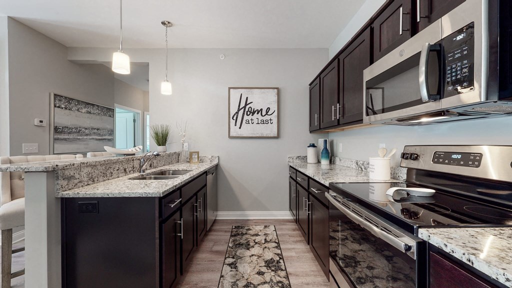 a kitchen with granite countertops and dark cabinets