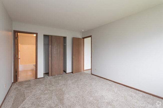an empty room with a carpeted floor and three doors