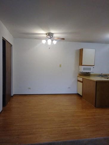 an empty room with a kitchen and a ceiling fan