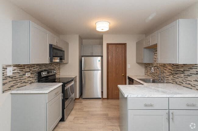 a kitchen with white cabinets and a stainless steel refrigerator