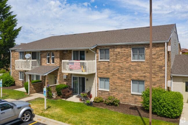 a brick apartment building with a balcony and a car parked in front