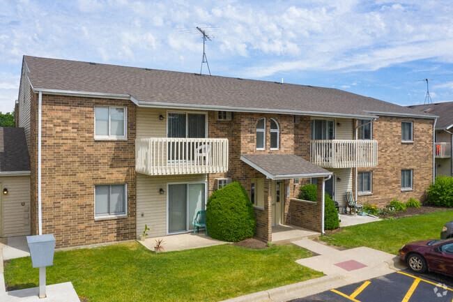 a brick apartment building with a porch and a lawn