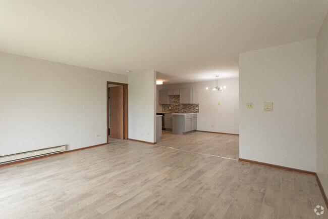 an empty living room and kitchen with a wood floor