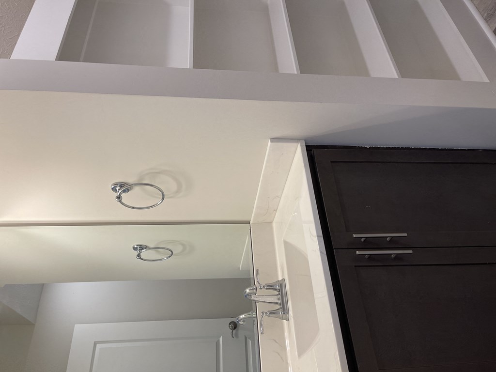 a bathroom with a white wall and a mirror and a cabinet
