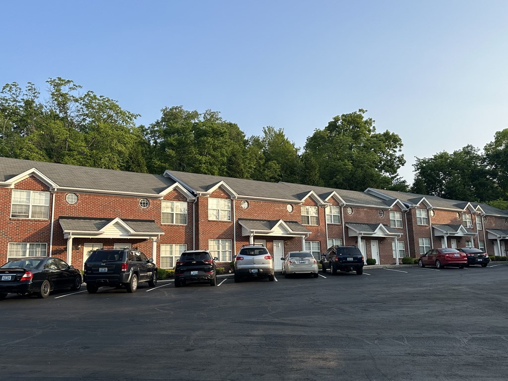 a parking lot filled with cars in front of a brick apartment building