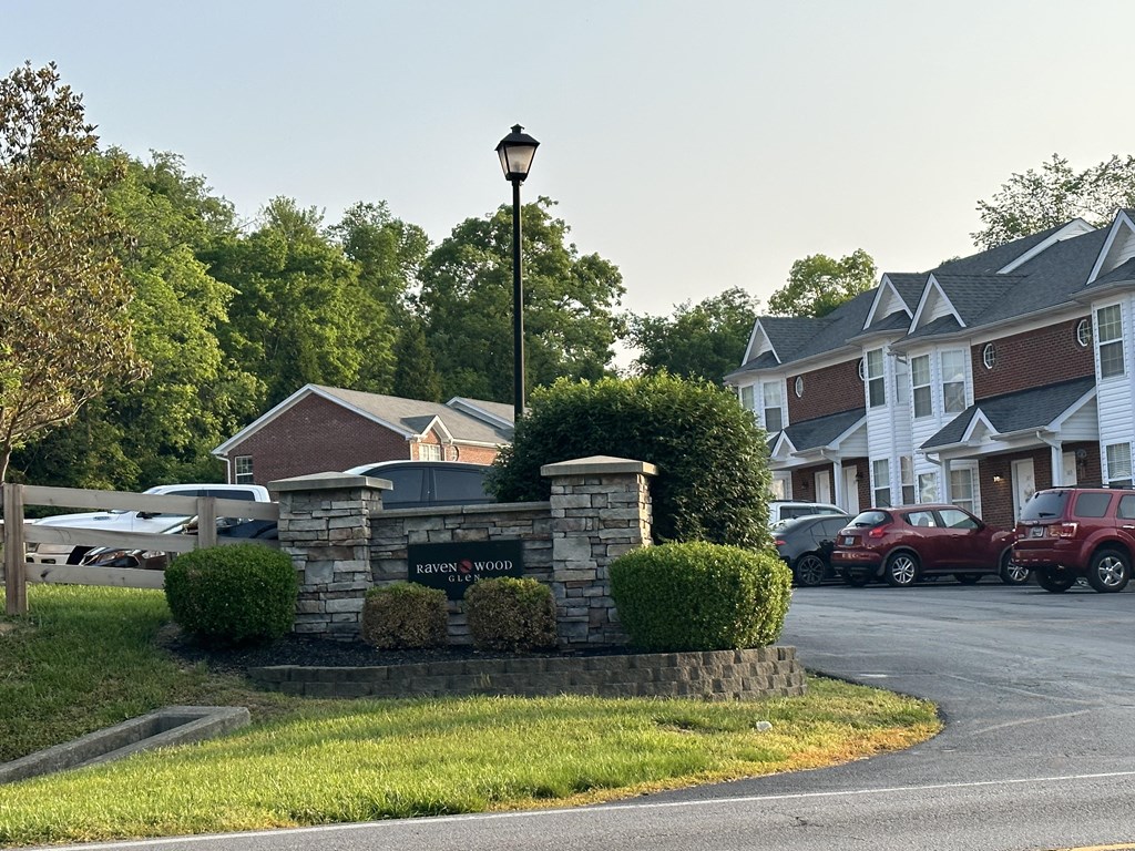 the front yard of a house with a parking lot and a street sign