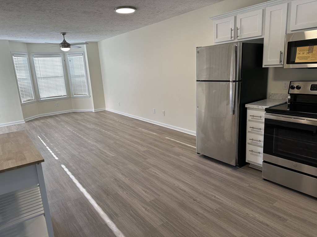 an empty kitchen and living room with a stainless steel refrigerator