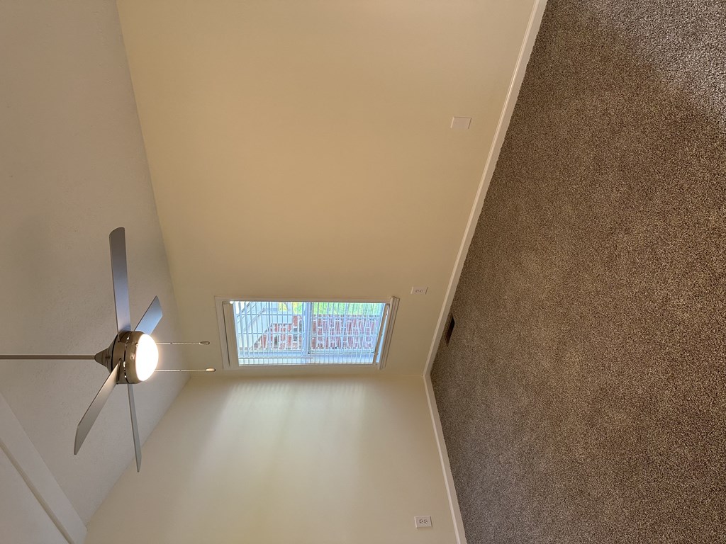 a ceiling fan in the corner of a room with a window