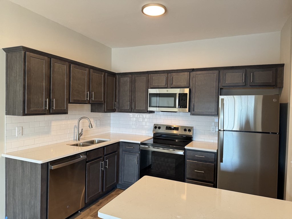 A kitchen with dark brown cabinets and stainless steel appliances.