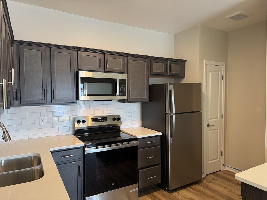 A kitchen with black cabinets and stainless steel appliances.