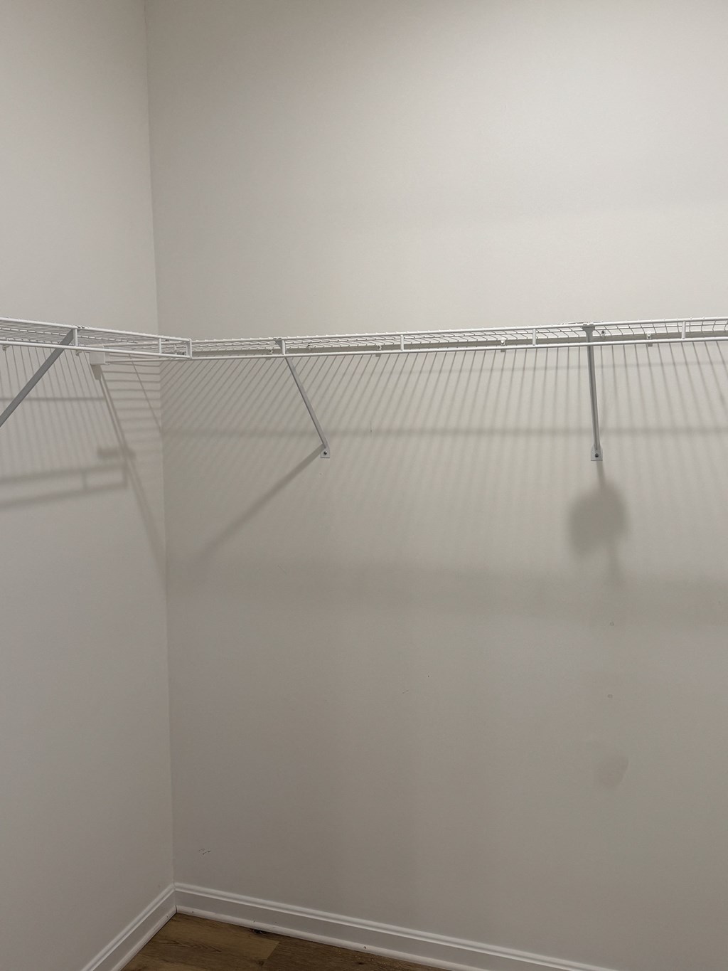A white wall with a metal rack hanging on it.