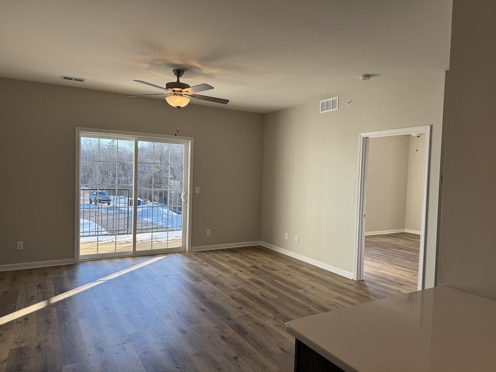 A room with a ceiling fan and sliding glass doors.