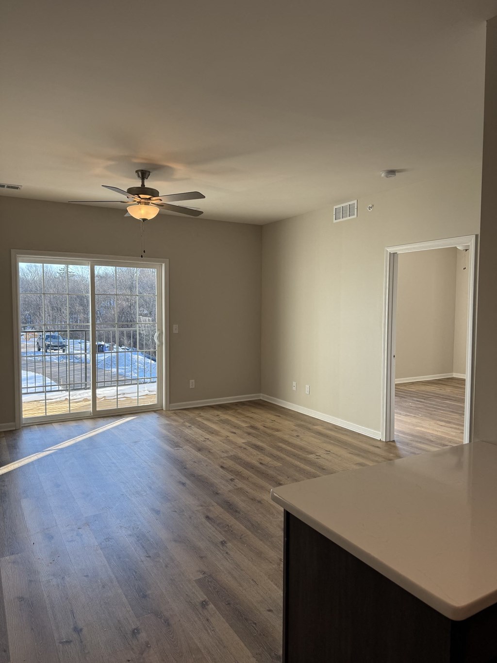 A room with a ceiling fan and sliding glass doors.